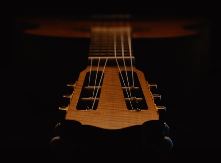Artistic close-up of a classical guitar's strings and headstock captured in low light ambiance.