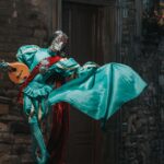 Colorful costumed performer brings Venice carnival charm with a ukulele on a cobblestone street.