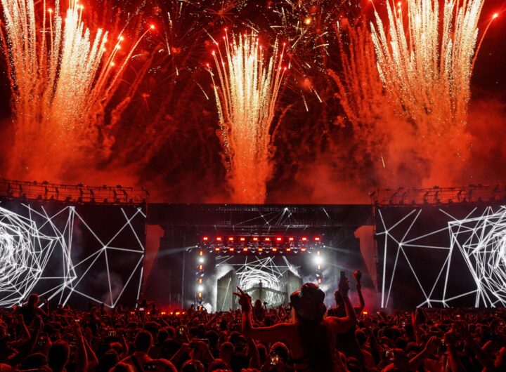 Vibrant festival concert scene with fireworks lighting up the night sky and a lively audience.