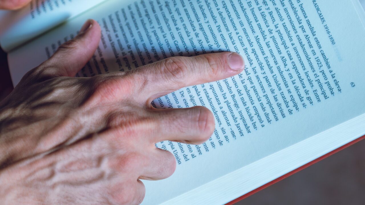 Detailed shot of a person reading a book, focusing on hand and text, in Buenos Aires, Argentina.