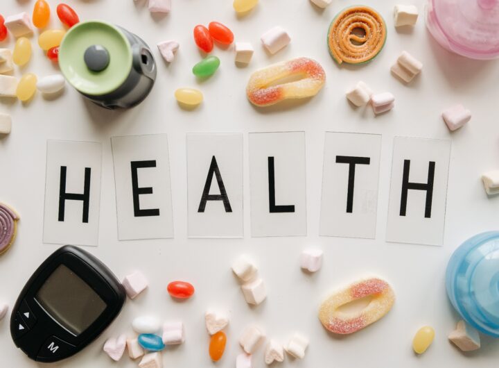 Creative flat lay with sweets around a 'HEALTH' text and monitoring device, symbolizing diabetes awareness.